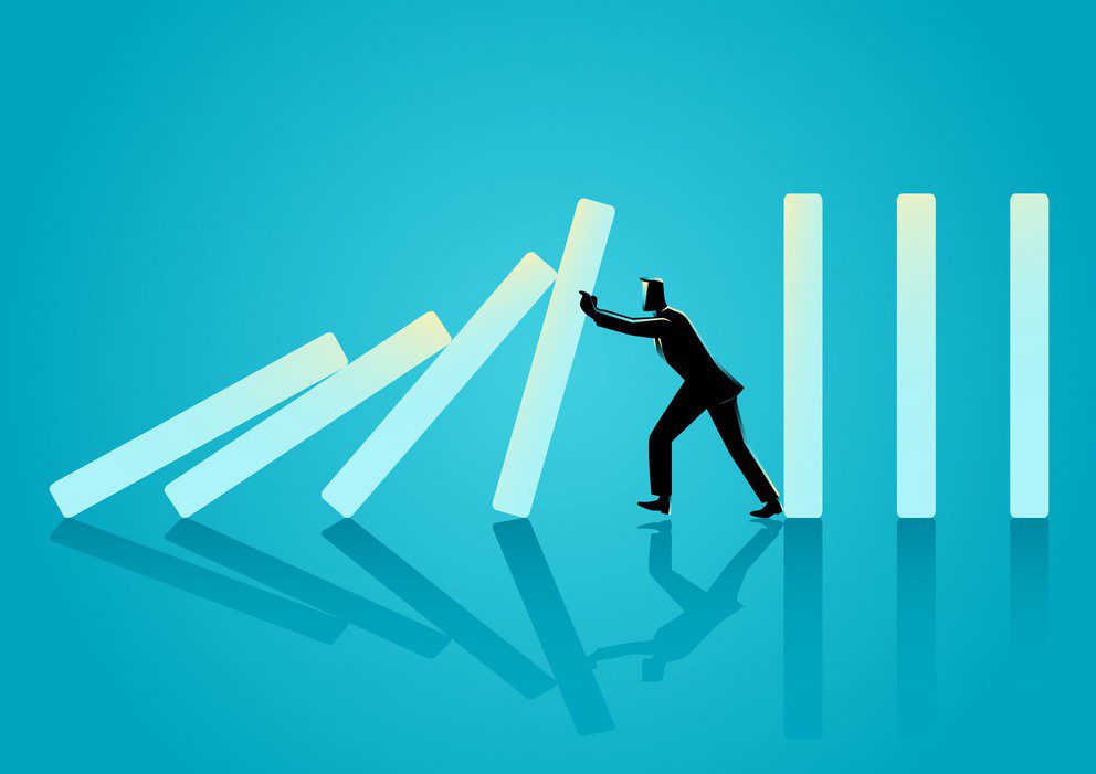 Businessman trying to stop domino effect